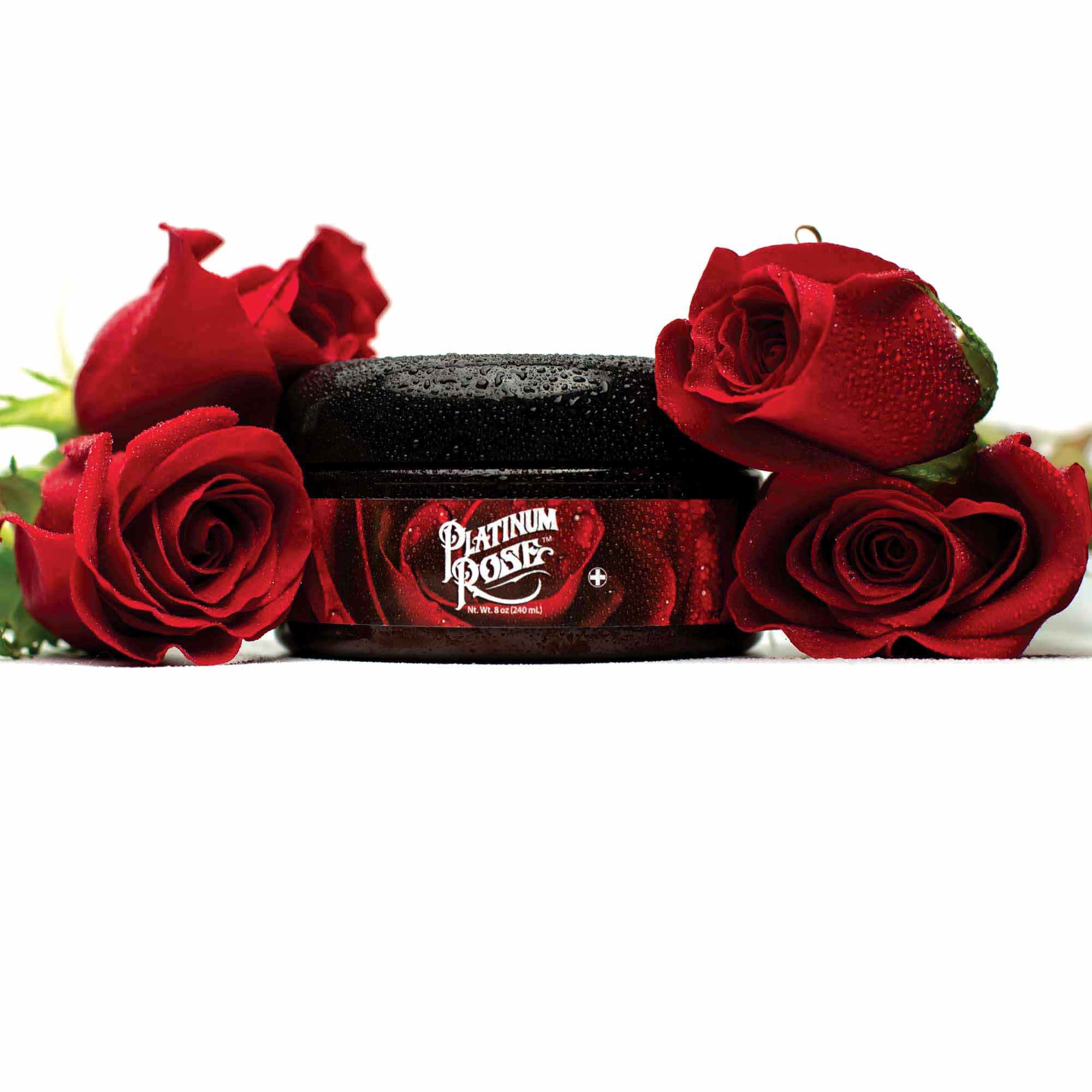 An 8oz Jar of rose scented Platinum Rose Tattoo Aftercare surrounded by freshly cut red roses